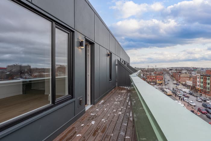 Balcony view of a cityscape under a partly cloudy sky from a modern building.