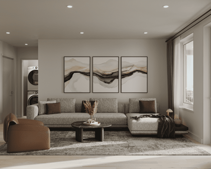 Modern living room with a grey sofa, abstract wall art, and a view of an adjacent laundry area.